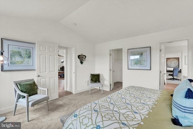 carpeted bedroom featuring a spacious closet, a closet, and lofted ceiling