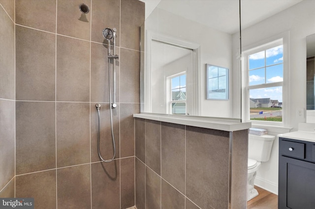 bathroom with tiled shower, toilet, vanity, and hardwood / wood-style flooring