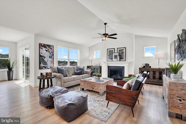 living room with a wealth of natural light, ceiling fan, light hardwood / wood-style floors, and lofted ceiling