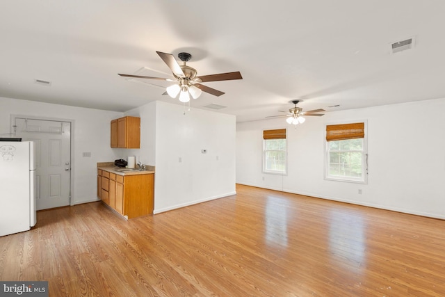 unfurnished living room with ceiling fan, light hardwood / wood-style flooring, and sink