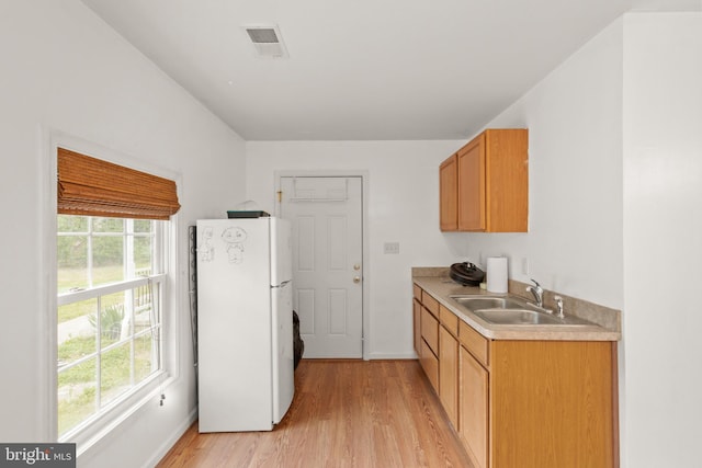 kitchen with white fridge, light wood-type flooring, sink, and a wealth of natural light