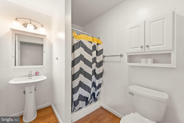 bathroom featuring hardwood / wood-style flooring, curtained shower, toilet, and sink