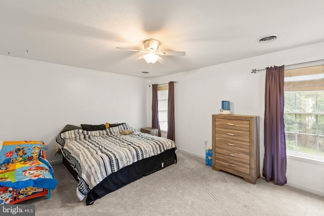 carpeted bedroom with ceiling fan and a textured ceiling