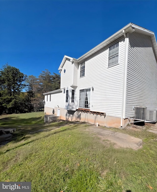 back of house featuring a lawn and cooling unit