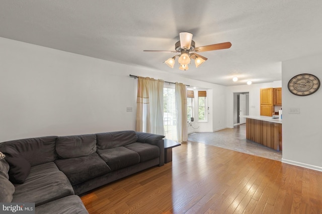 living room with ceiling fan, light hardwood / wood-style floors, and a textured ceiling