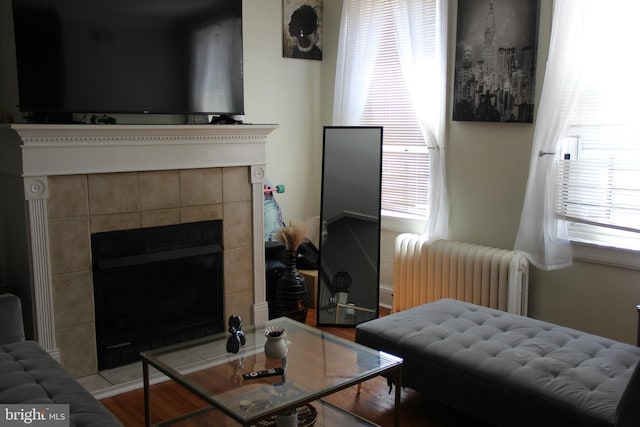 living room with a tile fireplace, radiator heating unit, and light hardwood / wood-style flooring