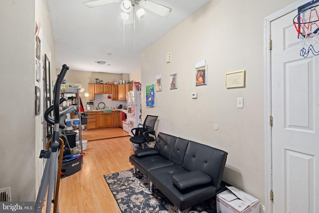 sitting room with ceiling fan, light hardwood / wood-style floors, and sink