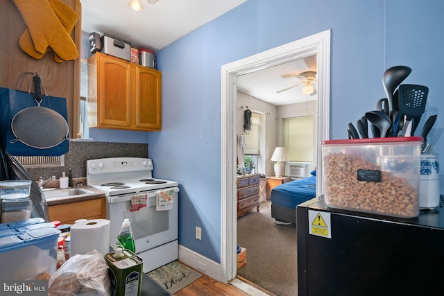 kitchen with hardwood / wood-style flooring, white range with electric stovetop, ceiling fan, an AC wall unit, and sink