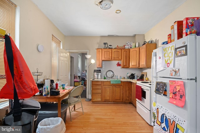 kitchen with light wood-type flooring, decorative backsplash, sink, and white appliances