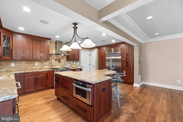 kitchen featuring a center island, light hardwood / wood-style floors, wall chimney range hood, and premium appliances