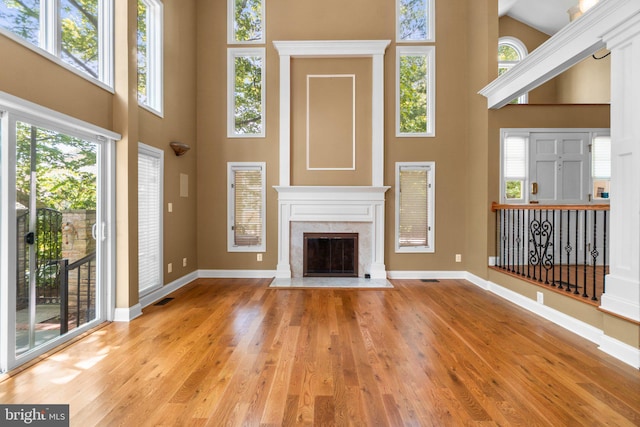 unfurnished living room with a fireplace, a high ceiling, and light wood-type flooring