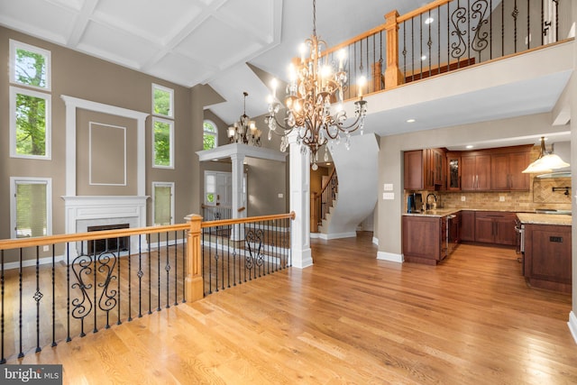 kitchen featuring coffered ceiling, decorative backsplash, a towering ceiling, and light hardwood / wood-style flooring