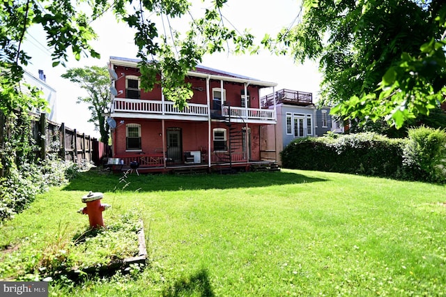 rear view of house with a yard and a balcony