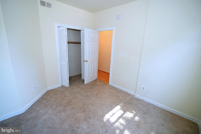 unfurnished bedroom with light colored carpet and a closet