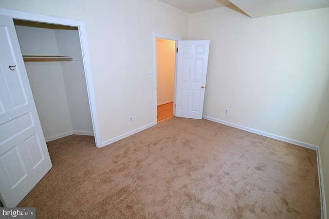 unfurnished bedroom with light carpet and a closet