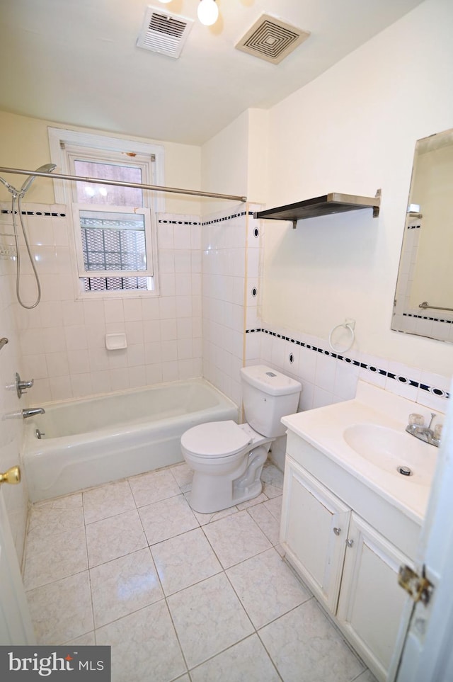 full bathroom with vanity, tiled shower / bath combo, tile walls, tile patterned flooring, and toilet