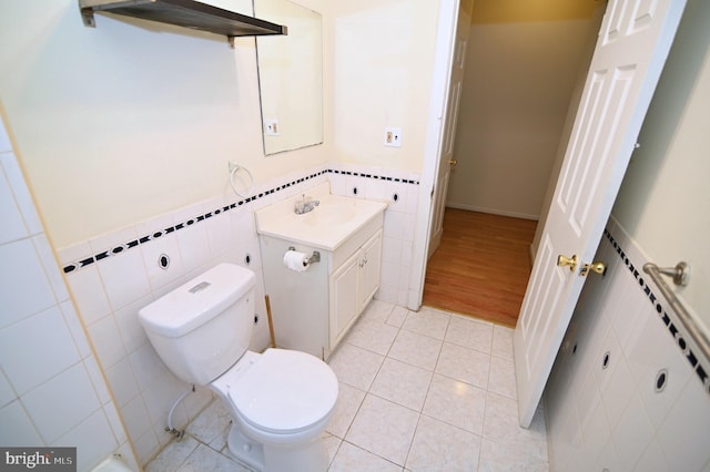 bathroom with tile patterned floors, vanity, tile walls, and toilet