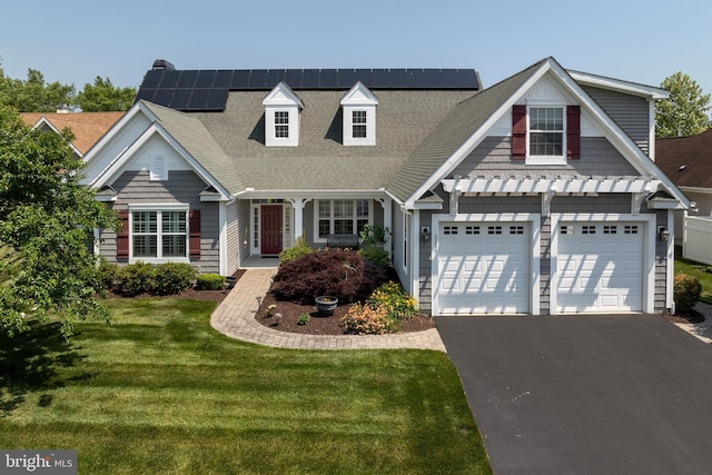 view of front of home with solar panels, a garage, and a front yard