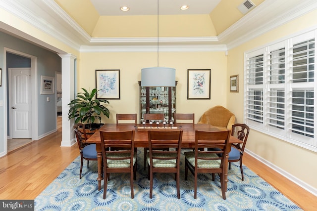 dining space with hardwood / wood-style flooring, a raised ceiling, and ornamental molding