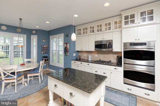 kitchen featuring white cabinets, a center island, stainless steel appliances, and hanging light fixtures