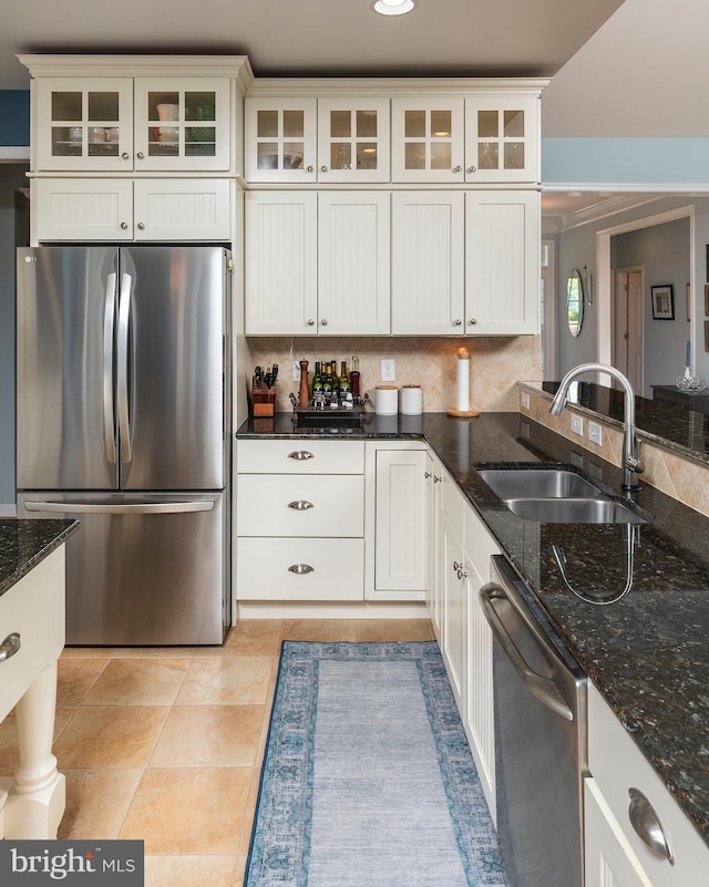 kitchen featuring dark stone counters, sink, decorative backsplash, white cabinetry, and stainless steel appliances