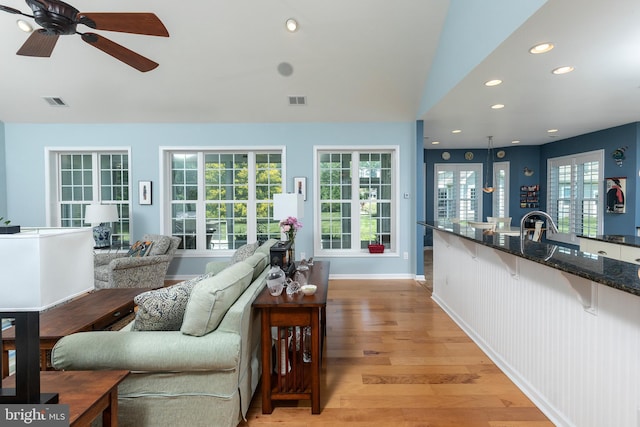 living room with ceiling fan, lofted ceiling, and light hardwood / wood-style flooring