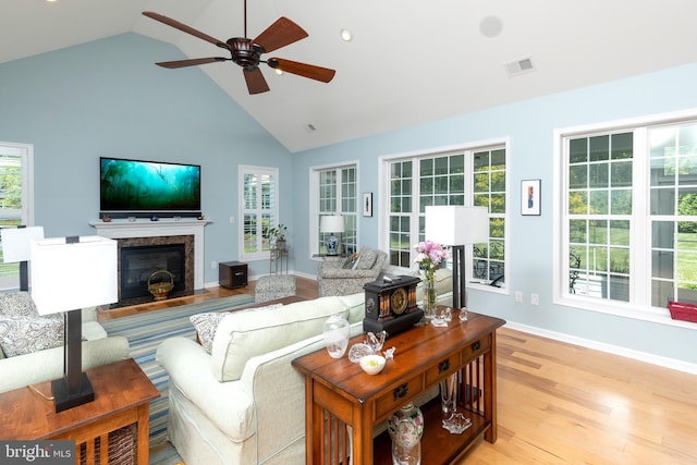 living room featuring high vaulted ceiling, ceiling fan, light hardwood / wood-style floors, and a high end fireplace