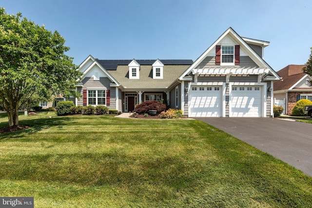 view of front of property featuring a front lawn, a garage, and solar panels