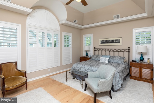 bedroom featuring hardwood / wood-style floors, ceiling fan, and multiple windows