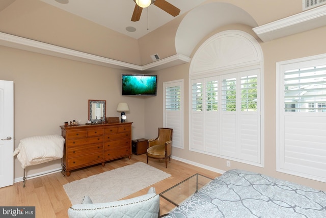 living area with a towering ceiling, light hardwood / wood-style floors, and ceiling fan