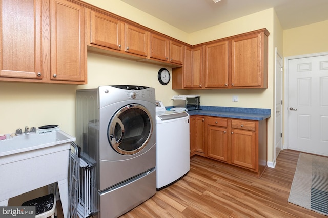 clothes washing area featuring cabinets, light hardwood / wood-style floors, and washing machine and dryer