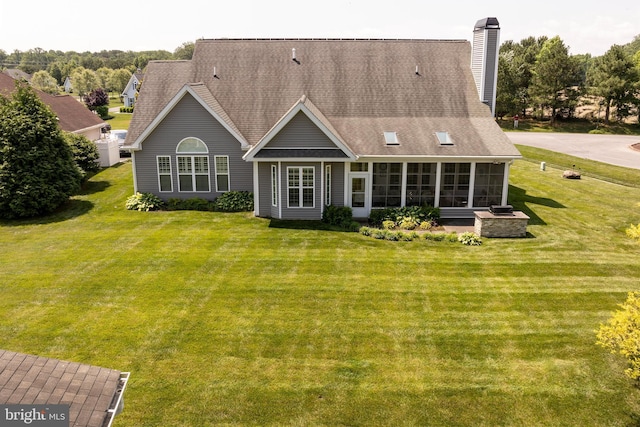 rear view of property featuring a sunroom and a yard