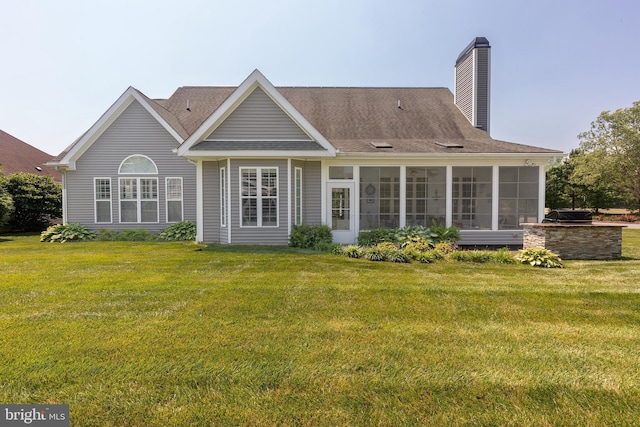 rear view of house featuring a sunroom and a yard