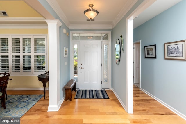 entrance foyer featuring light wood-type flooring, a wealth of natural light, and ornamental molding