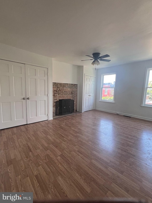 unfurnished living room with ceiling fan, wood-type flooring, and a brick fireplace