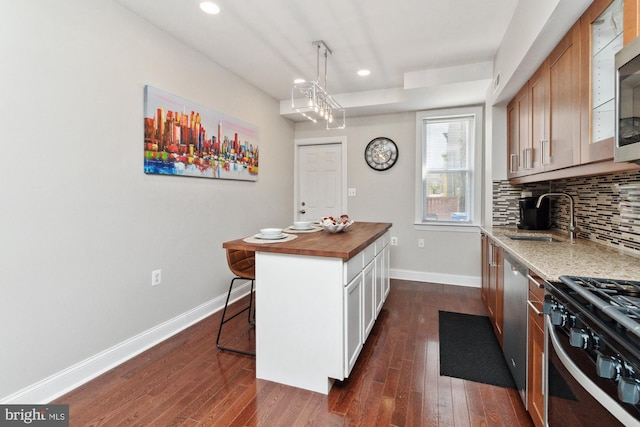 kitchen featuring sink, stainless steel appliances, wood counters, dark hardwood / wood-style flooring, and a breakfast bar area