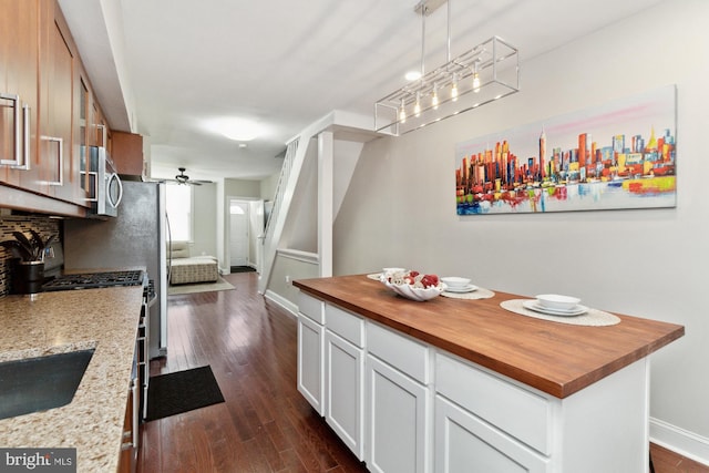 kitchen featuring a center island, white cabinets, hanging light fixtures, dark hardwood / wood-style floors, and appliances with stainless steel finishes