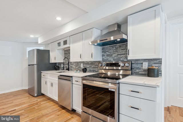 kitchen featuring wall chimney exhaust hood, light wood-type flooring, sink, and appliances with stainless steel finishes