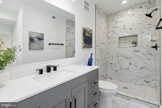 bathroom featuring a tile shower, vanity, and toilet