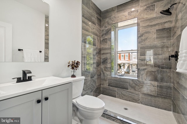 bathroom with vanity, toilet, and a tile shower