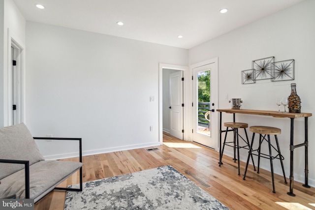 sitting room featuring bar area and light wood-type flooring