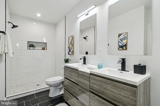 bathroom with tiled shower, vanity, and toilet