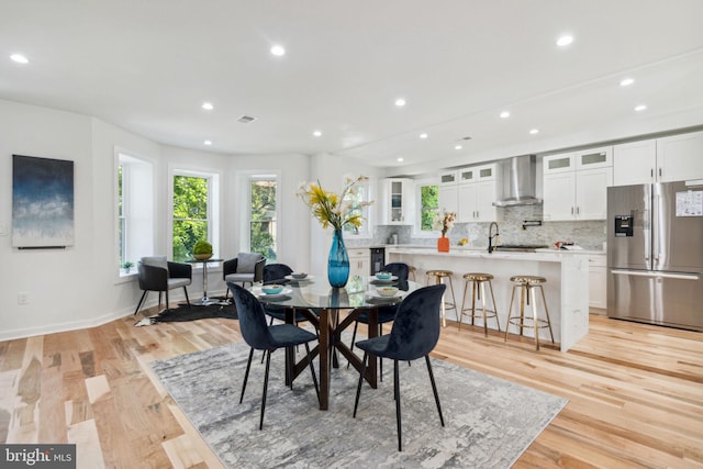 dining room with light wood-type flooring, sink, and beverage cooler