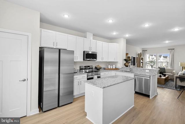 kitchen featuring kitchen peninsula, white cabinets, stainless steel appliances, and light wood-type flooring