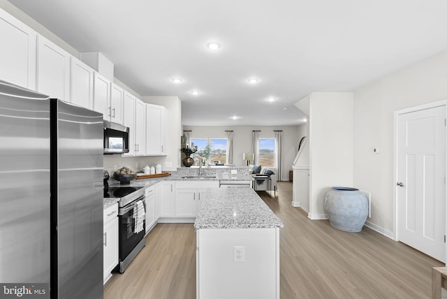 kitchen featuring white cabinets, light stone countertops, stainless steel appliances, and light hardwood / wood-style flooring