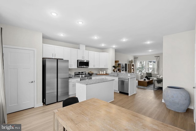 kitchen with kitchen peninsula, light stone counters, stainless steel appliances, and light hardwood / wood-style floors