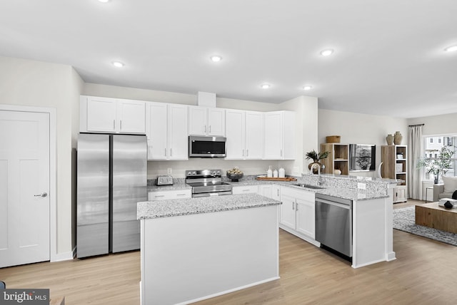 kitchen with white cabinetry, stainless steel appliances, sink, kitchen peninsula, and light wood-type flooring