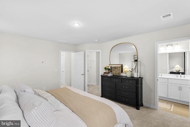 bedroom with light colored carpet, sink, and connected bathroom