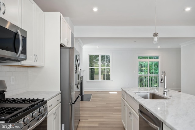 kitchen featuring decorative light fixtures, stainless steel appliances, white cabinets, and sink