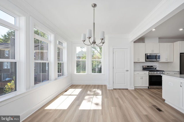 kitchen featuring decorative light fixtures, white cabinets, tasteful backsplash, a chandelier, and appliances with stainless steel finishes